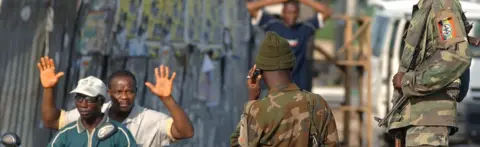 AFP A man on a motorbike travels past soldiers with his hands in the air, in Yenagoa, Bayelsa State - 2007