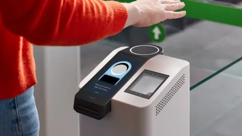 Amazon A person's arm and torso in frame show them holding a hand over a scanning terminal which has a ring pointing upwards, and the instruction to "move your palm to align the circles"