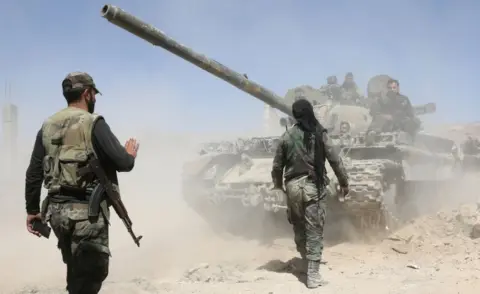 AFP/Getty Images Pro-government troops on foot and riding on a tank as they advance towards the town of Douma on 7 April