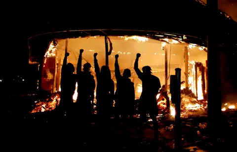 Reuters Protesters are seen outside of a liquor store on fire