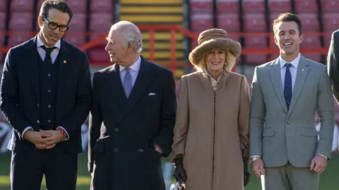 Arthur Edwards/The Sun King Charles III and the Queen Consort during their visit to Wrexham Association Football Club's Racecourse Ground, meeting owners and Hollywood actors, Ryan Reynolds (left) and Rob McElhenney (right), and players to learn about the redevelopment of the club