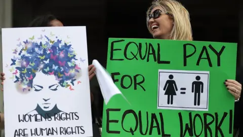 Getty Images Elana Goodman joins with other protesters to ask that woman be given the chance to have equal pay as their male co-workers on March 14, 2017 in Fort Lauderdale, Florida. The protest was held as the legislation in the state of Florida looks at passing the Helen Gordon Davis fair pay protection act that would strengthen state laws in terms of equal pay.