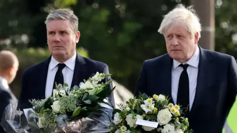 Getty Images Sir Keir and Mr Johnson standing with flowers