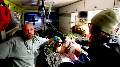 BBC / Darren Conway Ruslan and Olia accompany Sasha in the ambulance