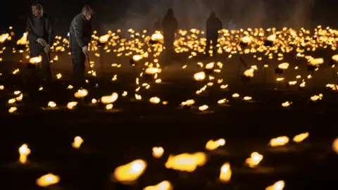 Getty Images Volunteers light torches in the moat of the Tower of London