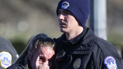 AFP via Getty Images A male and female police officer mourn after the Capitol riot