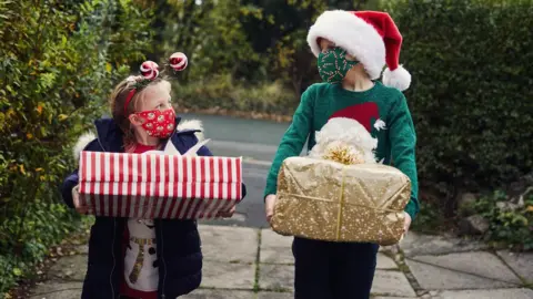 Getty Images Children with Christmas presents and face coverings