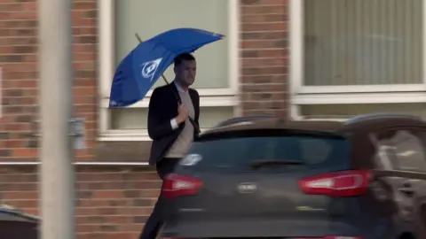 Qays Najm/BBC Daniel Reynolds outside Norwich Crown Court holding a blue umbrella