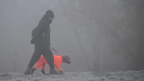 Getty Images A dog walker makes their way through fog on a frosty morning at Primrose Hill in north London on December 11, 2022