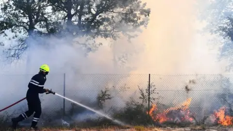 AFP/Getty Images A firefighter battles a fire in Artigues, south-eastern France. Photo: 25 July 2017