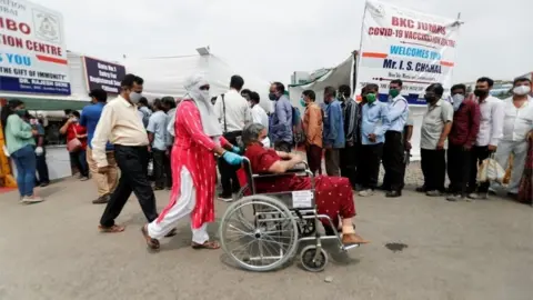 Reuters A woman in a wheelchair leaves a vaccination centre after receiving a dose of the coronavirus disease (COVID-19) vaccine during a vaccination drive, in Mumbai, India, April 8, 2021