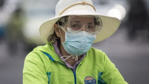 Getty Images A women wears a mask while riding a bicycle on May 11, 2020 in Wuhan, China.