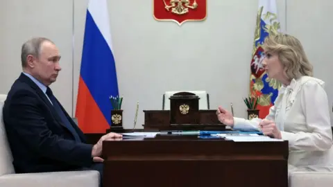 Getty Images Russian President Vladimir Putin meets with Maria Lvova-Belova, Russian children's rights commissioner, at the Novo-Ogaryovo state residence, outside Moscow, on February 16, 2023