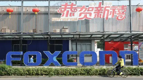 AFP/Getty This picture taken on February 22, 2013 shows people walking past a Foxconn recruitment point in Shenzhen, south China's Guangdong province.