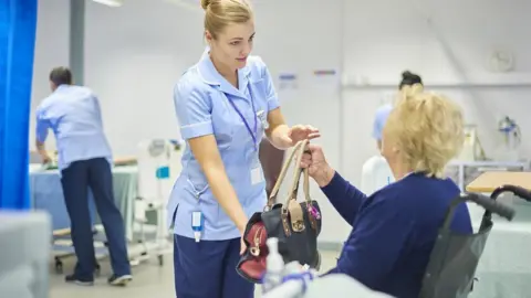 Getty Images A patient is handed her bag by a nurse