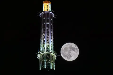 Getty Images A full moon rises behind the Canton Tower on July 3, 2023 in Guangzhou, Guangdong Province of China