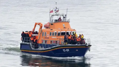 PA Media People thought to be migrants are rescued by the RNLI following the incident on board a small boat on Tuesday