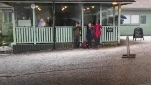 BBC People sheltering in Bodnant Gardens during a hailstorm earlier this month