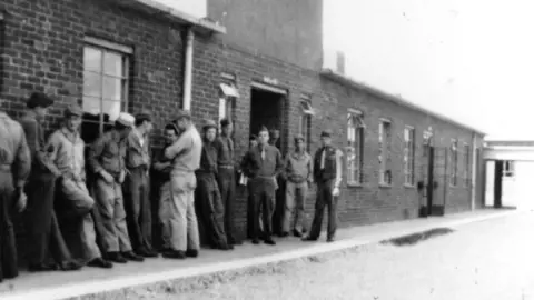 ArtCare, Salisbury District Hospital An old black and white photo of soldiers queuing outside a red brick building.