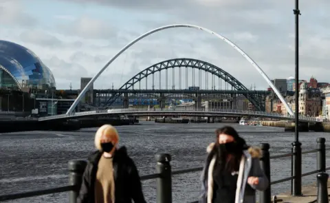 Reuters View of two women wearing masks with River Tyne bridges and the Sage Gateshead in the background