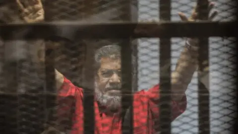 EPA Ousted Egyptian President Mohamed Morsi gestures during a trial session on charges of espionage in Cairo, Egypt, 18 June 2016