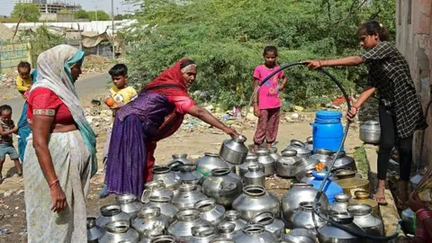 Getty Images A woman pours drinking water in a pot offered by a temple in the vicinity on a hot summer day on the outskirts of Ahmedabad