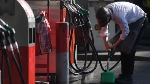 EPA Man fills up a can with petrol