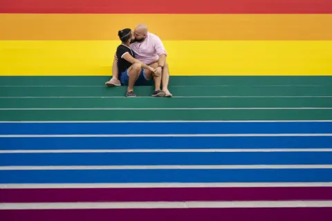 Drew Angerer / Getty Images Jesus Tavarez and Juan De La O kiss on the steps that are covered in rainbow colours for Pride Month at Franklin D. Roosevelt Four Freedoms Park in New York City in June.