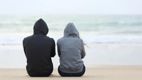 Getty Images Two teenagers wearing hooded tops with their backs to the cameras