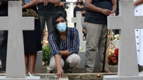 Relatives pay their respect at a graveyard for St. Sebastian's Church bomb blasts victims in Negombo on April 21, 2021, marking the second anniversary of the 2019 Easter Sunday attacks that killed 279 people at three churches and hotels