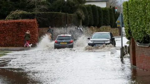 Reuters Cars drive through a flooded street in Great Barford, near Bedford,