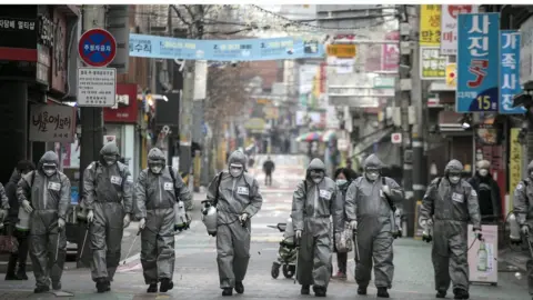 Getty Images workers in South Korea disinfect a street