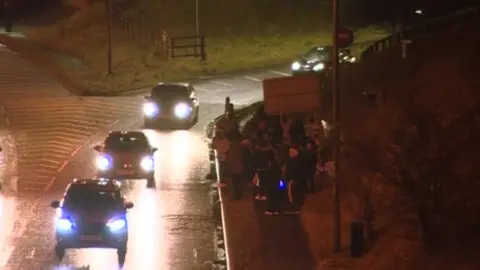 People gathered at a vigil by the side of a motorway