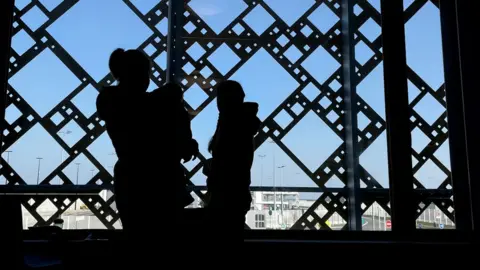 PA Media Members of a Ukrainian family wait for paperwork to be completed at the ferry terminal in Calais, France