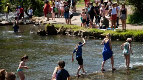 PA Media People walk across the River Dove in Dovedale in the Peak District