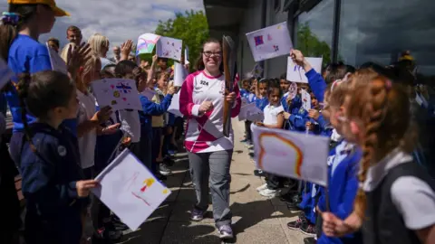 Getty Images Freya Cowie carries the baton in Stockton as she is cheered by onlookers