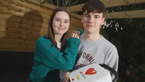 British Heart Foundation Lucy pictured with her brother Thomas and a defibrillator