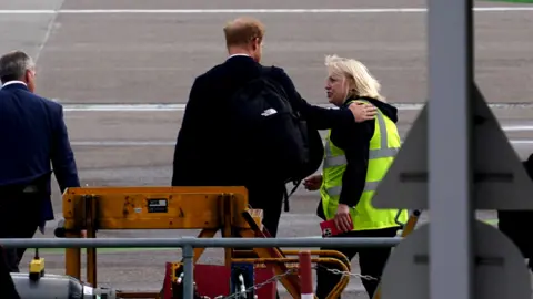 Getty Images Harry was seen putting his arm around an airport worker at Aberdeen airport as he travelled back to London early this morning.
