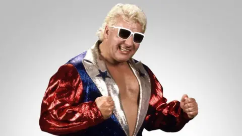 WWE Johnny Valiant, seen here in sunglasses and a sparkly jacket