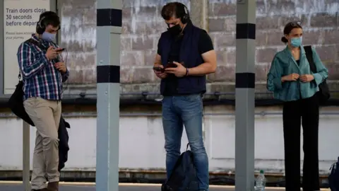 Getty Images Masked passengers waiting for trains