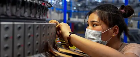 AFP An employee checking on a circular weaving machine at a textile factory in Shangqiu