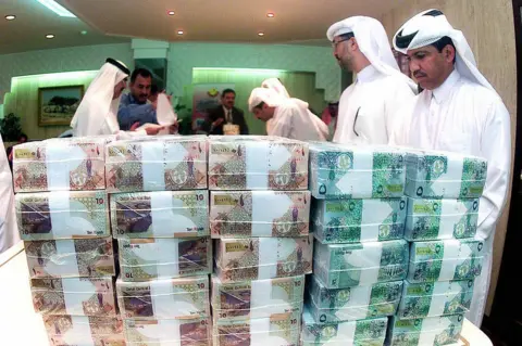 Getty Images Officials from the Qatar Central Bank count cash