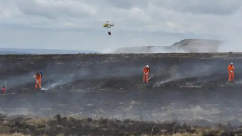 West Yorkshire Fire and Rescue Service A helicopter drops water on the fire