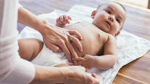 Getty Images baby having nappy put on