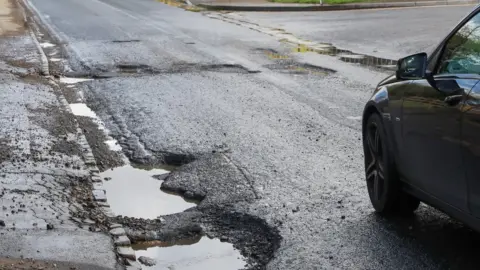 Getty Images A car next to a pothole in Slough