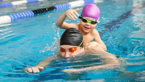 Man and young boy in swimming pool (stock photo)