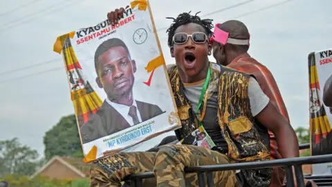 AFP Bobi Wine's supporter holds his campaign poster