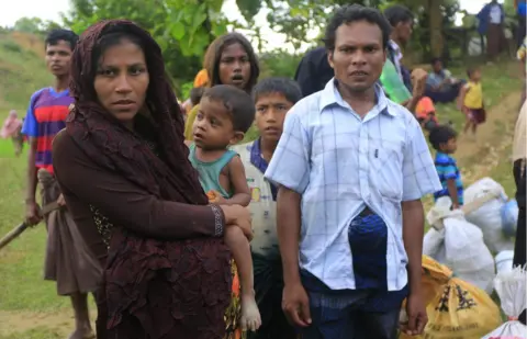 BBC Rasida, who is nine months pregnant, waits with her family as they look for a space to set up their makeshift home