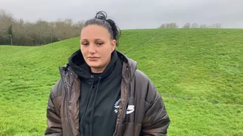 BBC Jordan Turner standing at the foot of the Venny a grass mound, in Pinehurst Swindon, where her brother, Lee Turner, lost his life