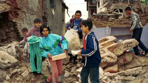 Getty Images Children carrying rubble from a house destroyed by the attacks